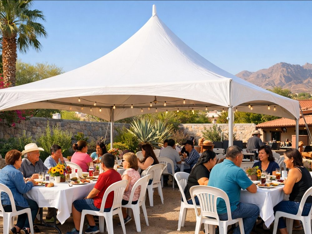 Families eating together under a white high-peak tent in an El Paso backyard, with the mountains in the distance.